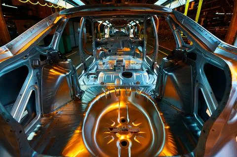 Metallic car carcasses on conveyor in assembling workshop Stock Photos