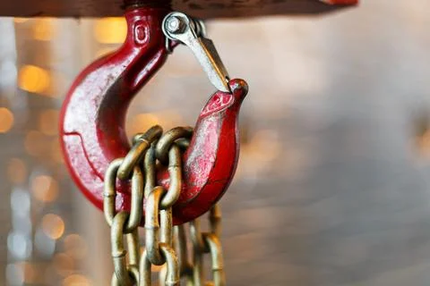 Metallic chain handle with red hook in technical room. Crane cargo hook. Photos