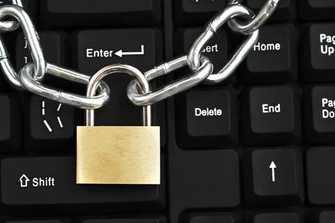 Metallic chain with a locked padlock on a computer keyboard. Stock Photos