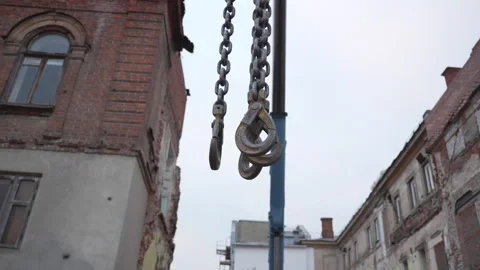 Metallic crane hooks swing between fragile aged stone walls Stock-Footage 316076218