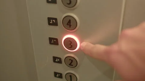 Metallic elevator interface lights up as button three is pressed by finger Stock Footage 325074047