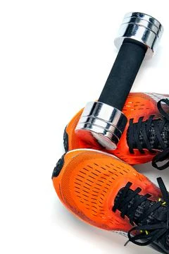 Metallic heavy dumbbell dropped on leg in orange sneaker isolated on white ba Stock Photos