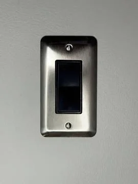 Metallic light switch on a plain wall in a home Stock Photos