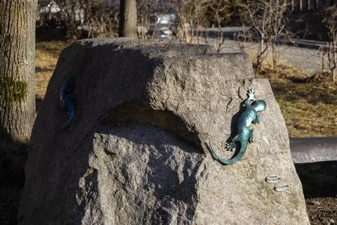Metallic lizard sculptures attached to a large granite rock in a park setting, Stock Photos