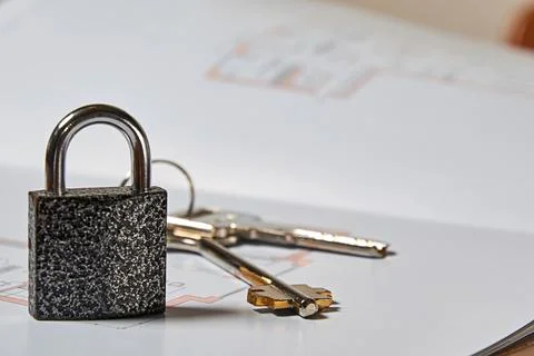 Metallic lock, keys and layout draft on apartment sale deal Stock Photos