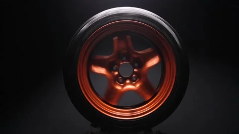 Metallic orange car wheels on a dark background Vidéo 234121096