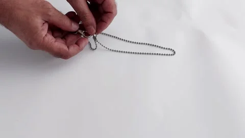 Metallic Pause: A Quiet Moment with Chain and Clasp in Soft Light Stock-Footage 315739412