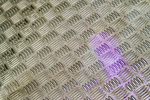 Metallic textured surface with diamond plate pattern and purple light refle.. Stock Photos