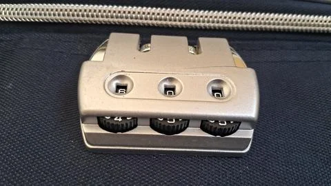 Metallic three digit combination suitcase lock on dark fabric background 写真素材
