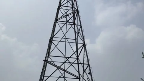 Metallic windmill structure standing tall against cloudy urban skyline. Stock Footage 336332027