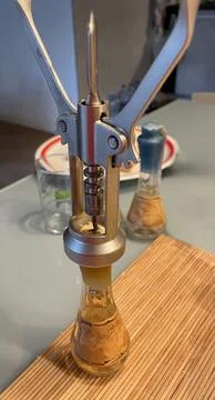 A metallic winged corkscrew inserted into the cork of a small decorative bottle Stock Photos
