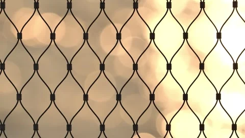 Metallic wire mesh pattern creating a geometric barrier with golden bokeh Stock Footage 344698629