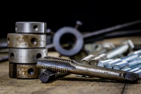 Metalwork tools on the workshop table. Threading dies and taps in an old dust Stock Photos