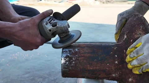 Metalworker cleaning rust from an industrial component with an angle grinder. Stock Footage 321357559