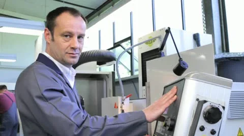Metalworker operates CNC machine - looks into the camera - 1 Stock Footage 11899879