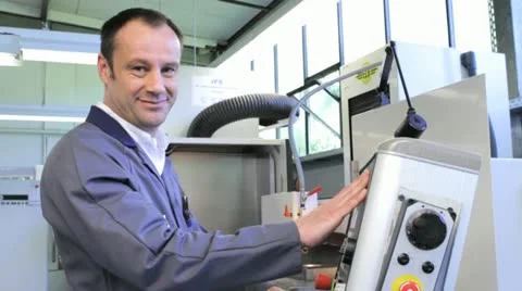 Metalworker operates CNC machine - looks into the camera - 10 Stock Footage 11899881