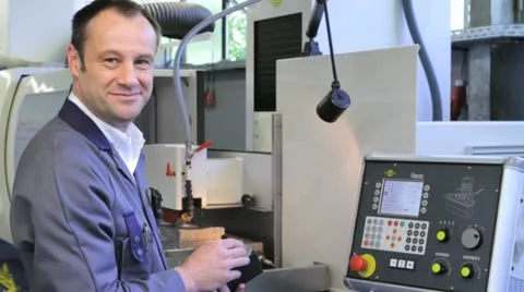 Metalworker operates CNC machine - looks into the camera - 4 Stock Footage 11899886