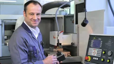 Metalworker operates CNC machine - looks into the camera - 6 Stock Footage 11899890