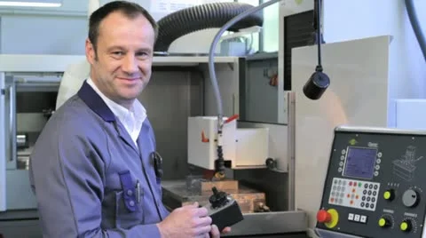 Metalworker operates CNC machine - looks into the camera - 7 Stock Footage 11899893