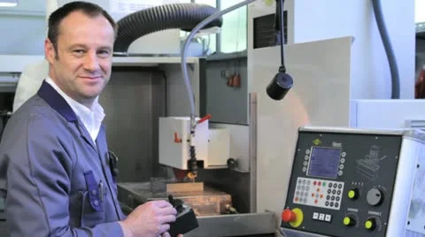 Metalworker operates CNC machine - looks into the camera - 8 Stock Footage 11899895