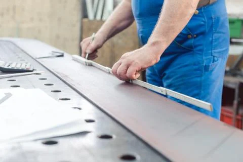 Metalworker using folding rule to measure steel strip 스톡 사진