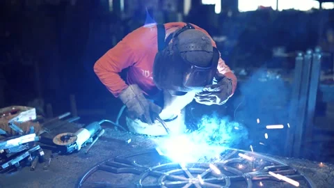 A metalworker welds an element of a metal structure with electric welding. Stock Footage 136357666