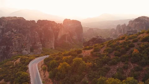 Meteora, Greece, at sunset. Lateral flight revealing the winding road and rocks Stock Footage