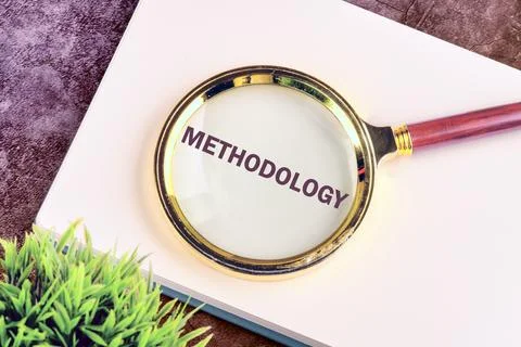 METHODOLOGY CONTEPT. METHODOLOGY word through a magnifying glass on a blank s Stock Photos