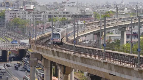 A metro train on a bridge passing through urban landscape  Stock Footage 241577570