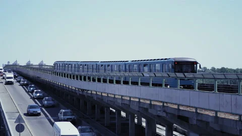 The metro train crosses the bridge over the river with moving cars in the Stock Footage 131381686