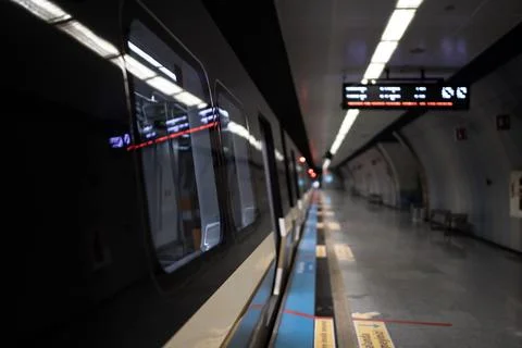 Metro train at an empty underground platform with a departure board Stock Photos