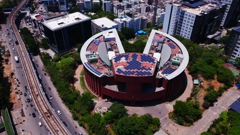 Metro train moving in front of TCS Deccan Park building with traffic flow and 库存影片 345114559