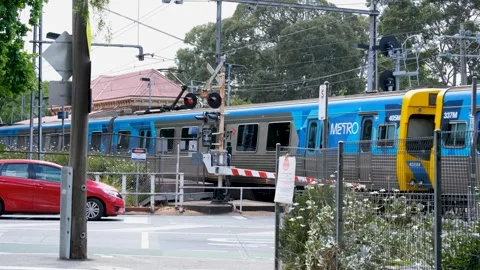 A Metro train passing a level crossing near Kensington Station in Melbourne Vídeos de archivo 295474312