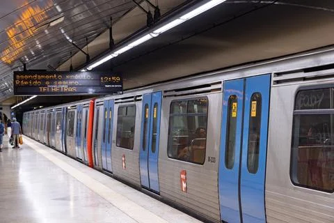 A metro train is at the platform, with a digital display board above showing Foto stock