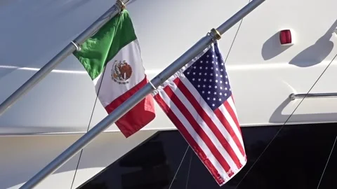 The Mexican and American flags fly side-by-side, signifying a connection Stock Footage 293516634
