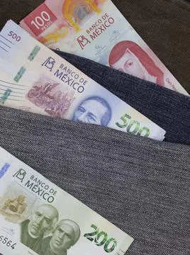 Mexican banknotes of different denomination between blue denim fabric Stock Photos