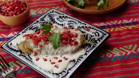 Mexican dish chile en nogada with red Mexican tablecloth, pan left Stock Footage 281991387