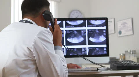 Mexican doctor viewing sonogram on computer while talking on phone Stock Footage 26178608