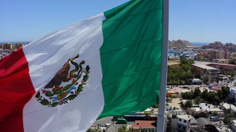 The Mexican flag blowing in the wind with Cabo San Lucas in the background Stock Footage 104653961