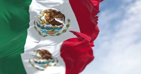 Mexican flags with its coat of arms waving against a blue sky. Stock Footage 327856968