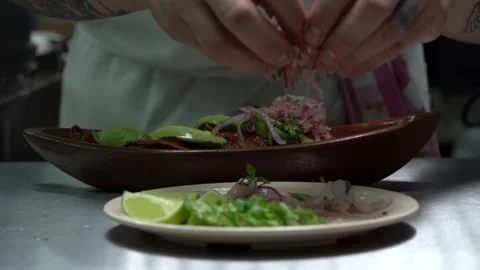 Mexican latin chef dressing hardshell tacos with red onion hot chili sauce Stock Footage 242389028