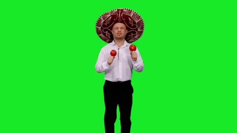 Mexican man in sombrero playing maracas against green screen background Video stock 133780153