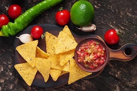 Mexican nacho chips and salsa dip in bowl on wooden background Stock Photos