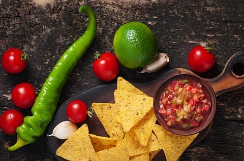 Mexican nacho chips and salsa dip in bowl on wooden background Stock Photos