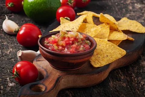 Mexican nacho chips and salsa dip in bowl on wooden background Stock Photos