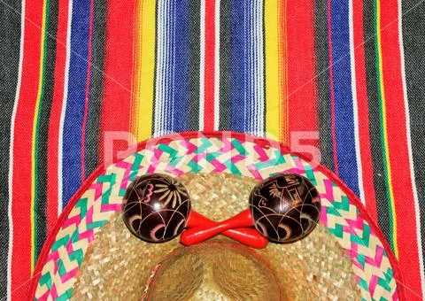 Mexican poncho serape background with sombrero and maracas Stock Photos