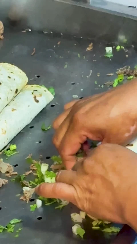 Mexican rolled tacos with cilantro and onion cooking on flat top grill 库存影片 330269853