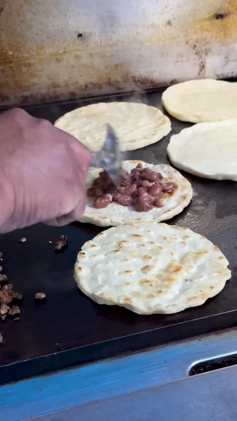 Mexican sopes with refried beans cooking on flat top grill\ Video stock 330269838