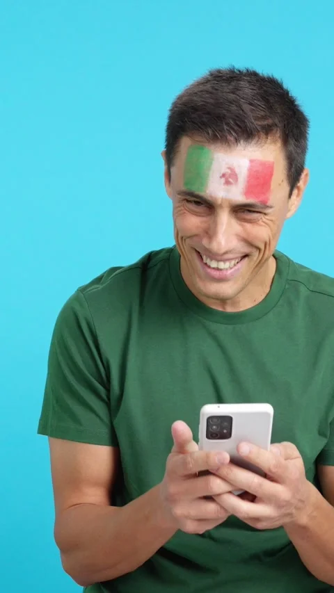 Mexican supporter looking at his mobile smiling and showing it. Stock Footage 275643448