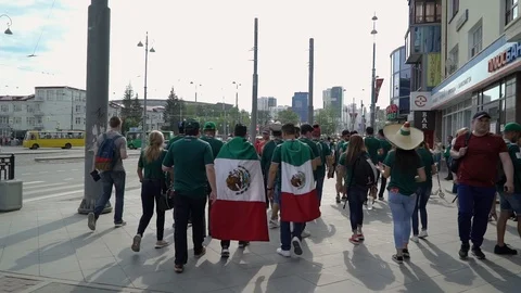 Mexican supporter wrapped in a flag walking down the street to the stadium Stock Footage 120501237